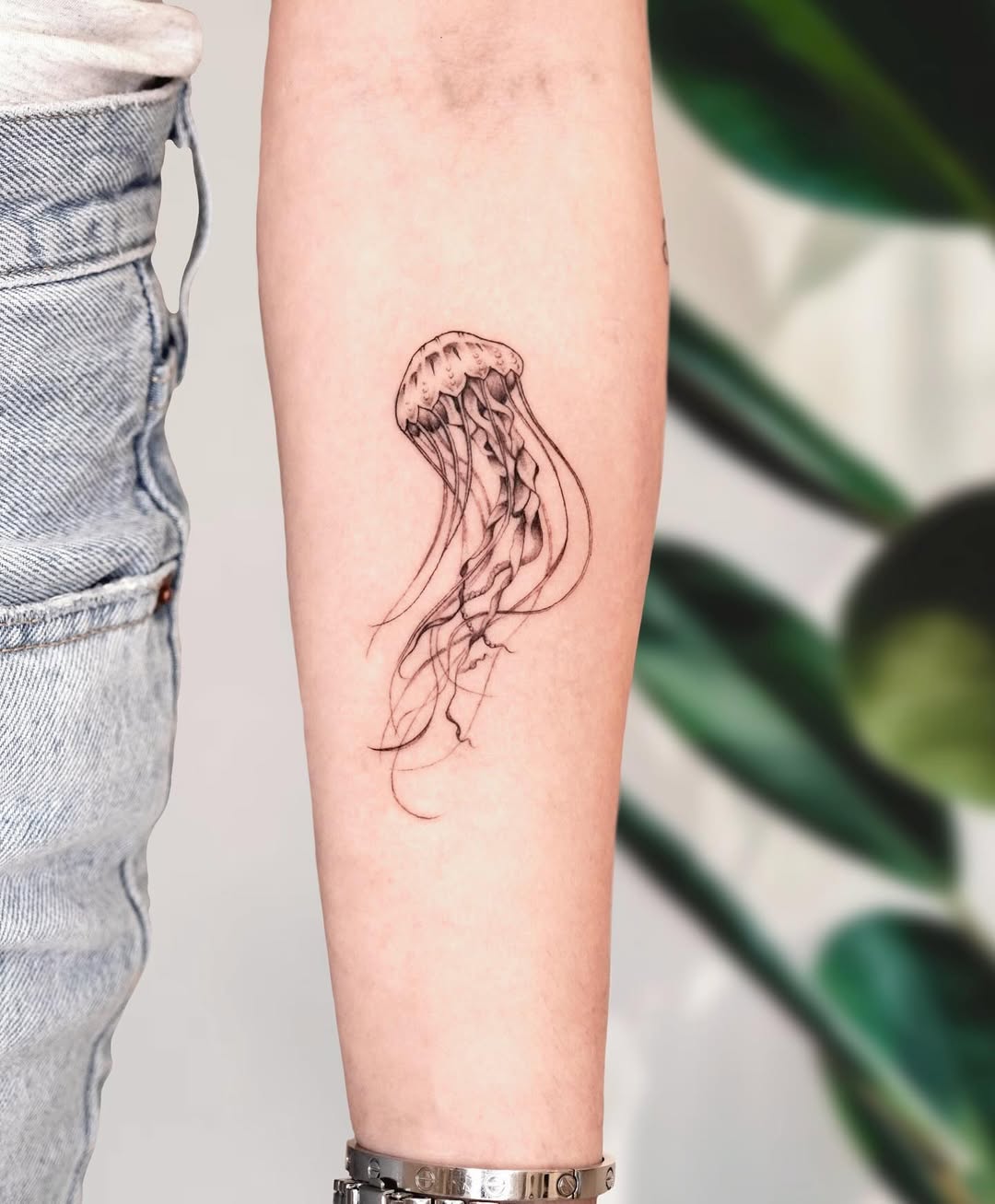 Minimalist jellyfish tattoo on the forearm