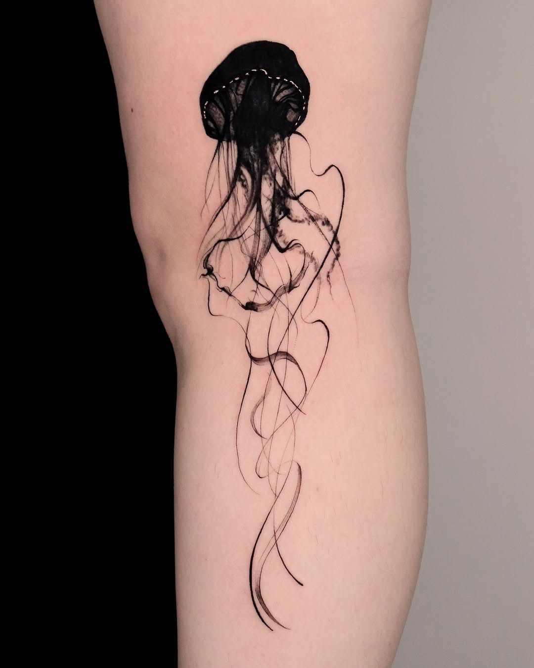 Elegant black jellyfish tattoo on the thigh