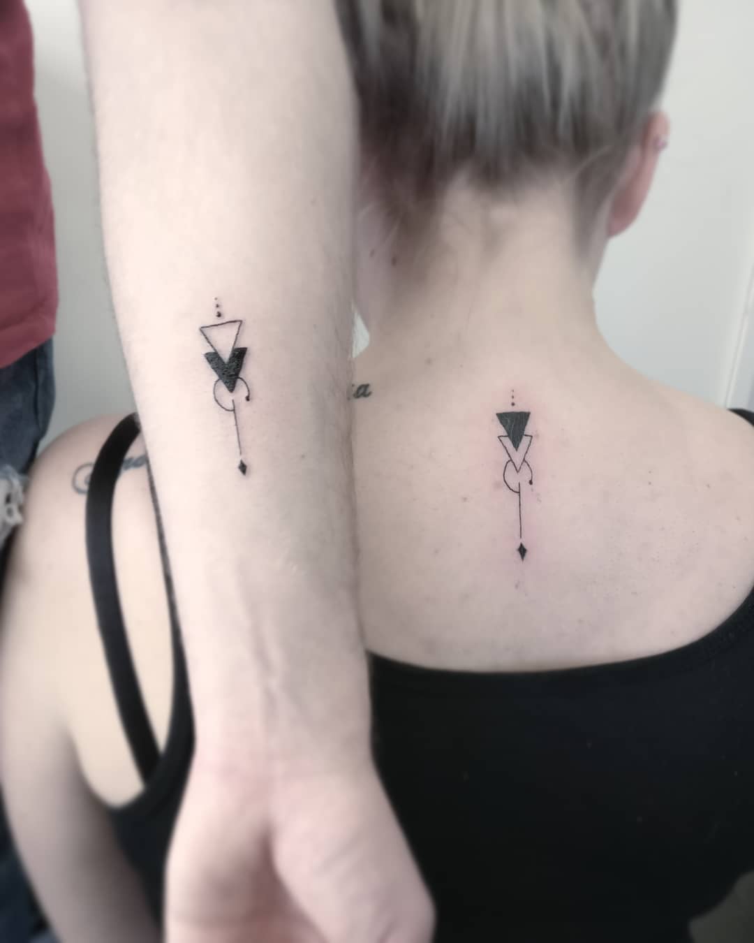 Stylish geometric tattoos connecting siblings