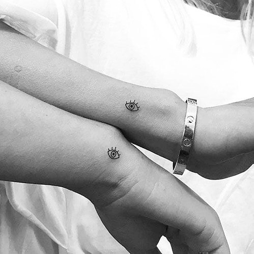 Minimalist twin eye tattoos on wrists