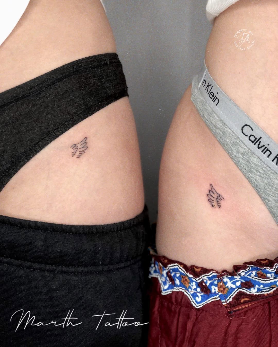 Matching small wing tattoos on twin sisters