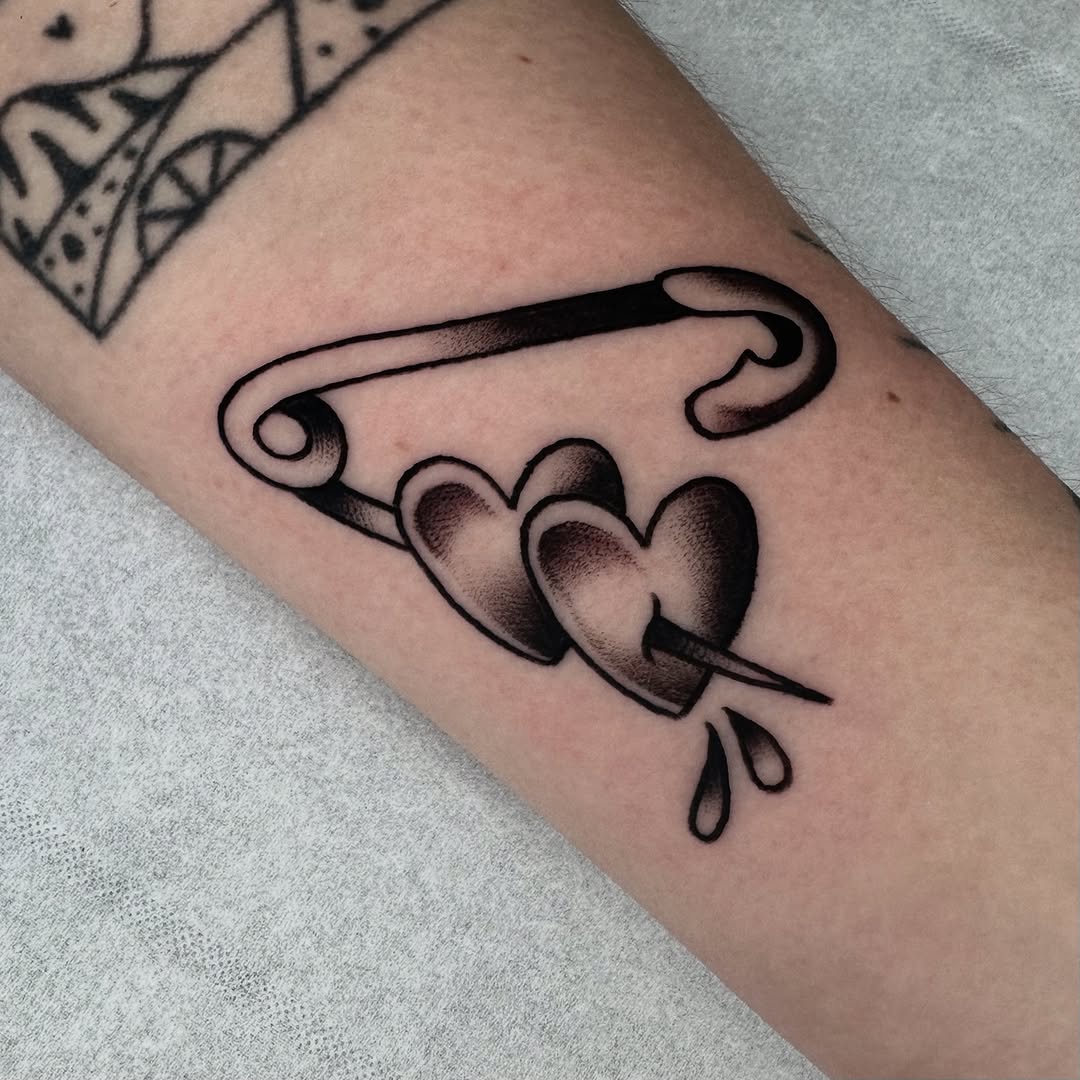 Charming hearts joined by a safety pin tattoo