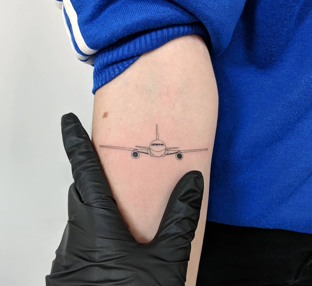 Minimalist airplane tattoo on the forearm
