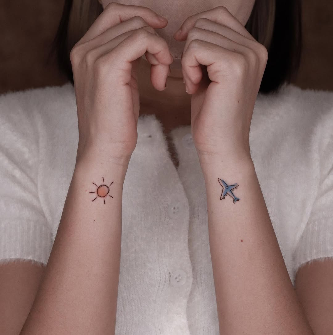 Minimalist airplane and sun tattoo on forearm
