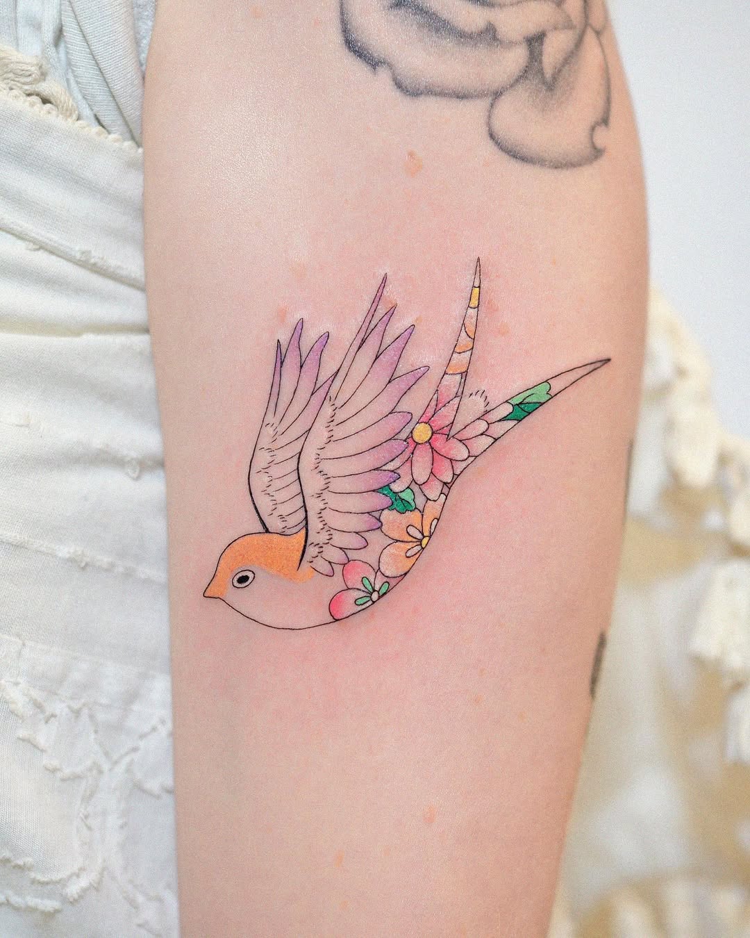 Vibrant swallow tattoo with floral elements