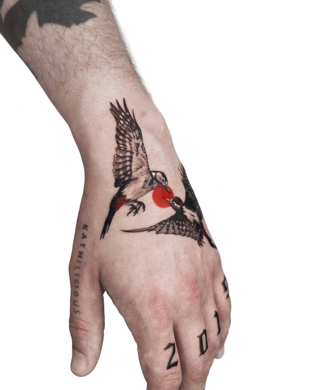 Vivid swallow tattoos take flight on hand.