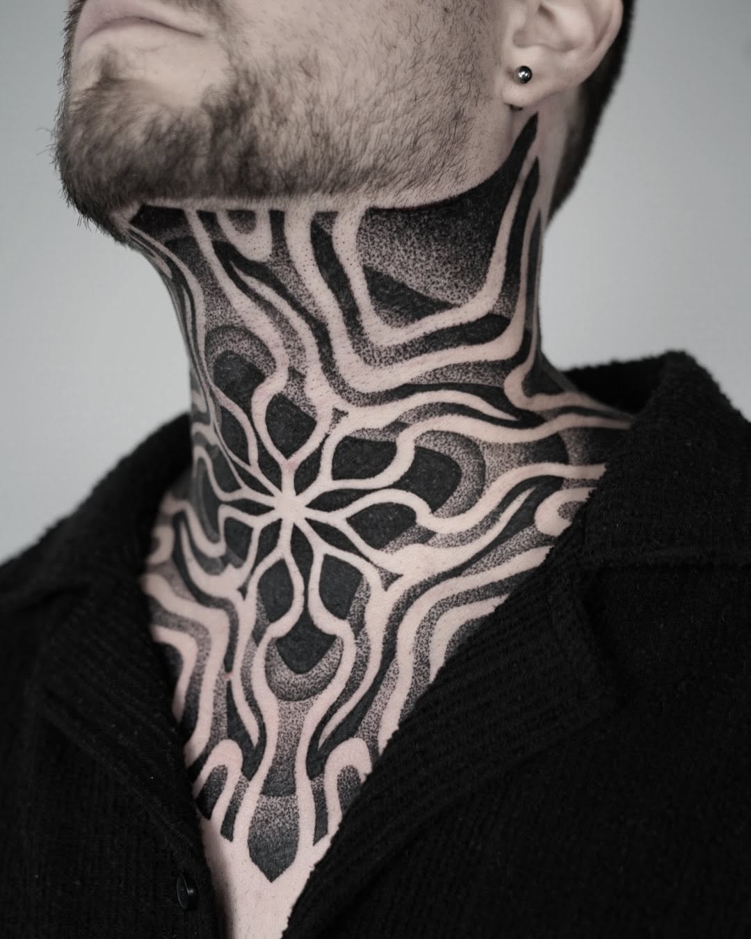 Artful black neck and chest tattoo design