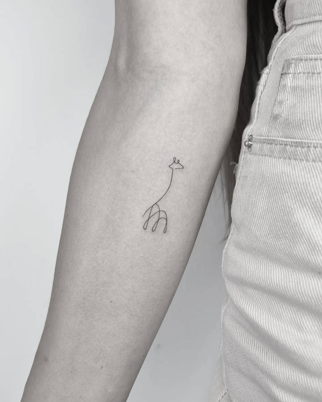 Charming minimalist giraffe one-line tattoo