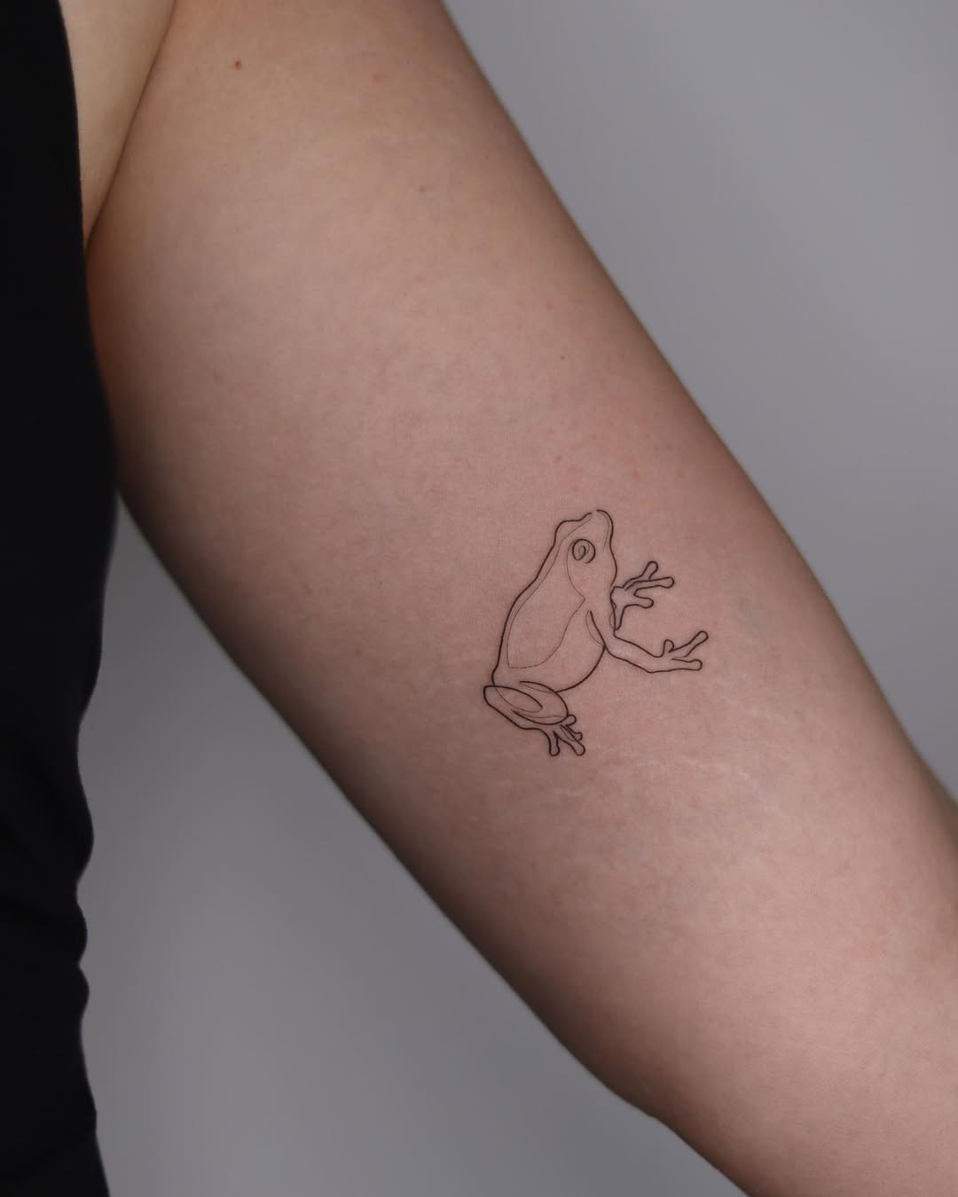 Minimalist frog tattoo in elegant one line style