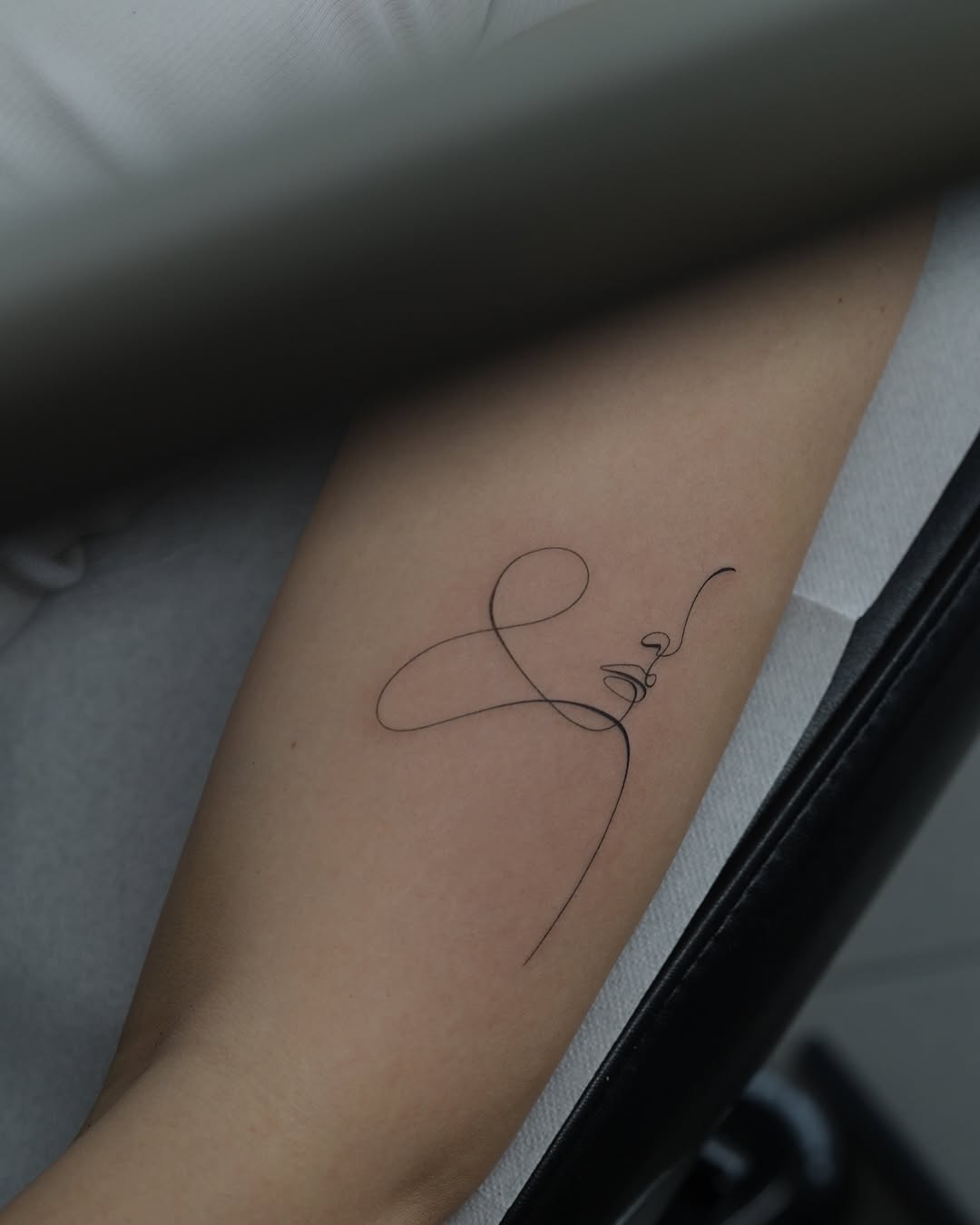 Elegant one-line signature tattoo design