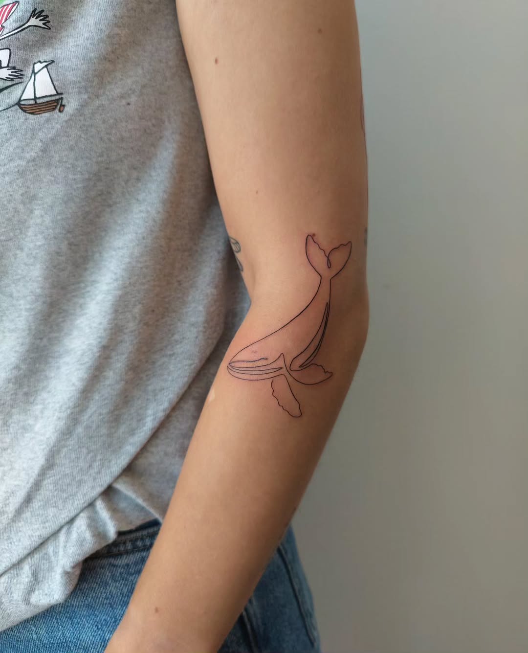 Minimalist whale tattoo on the forearm