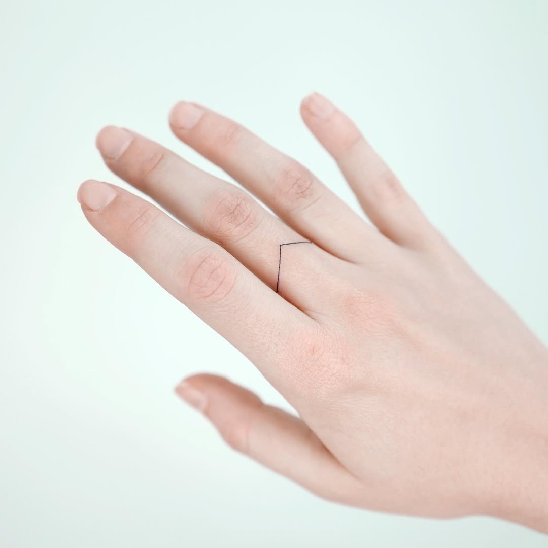 Minimalist line tattoo graces the finger elegantly