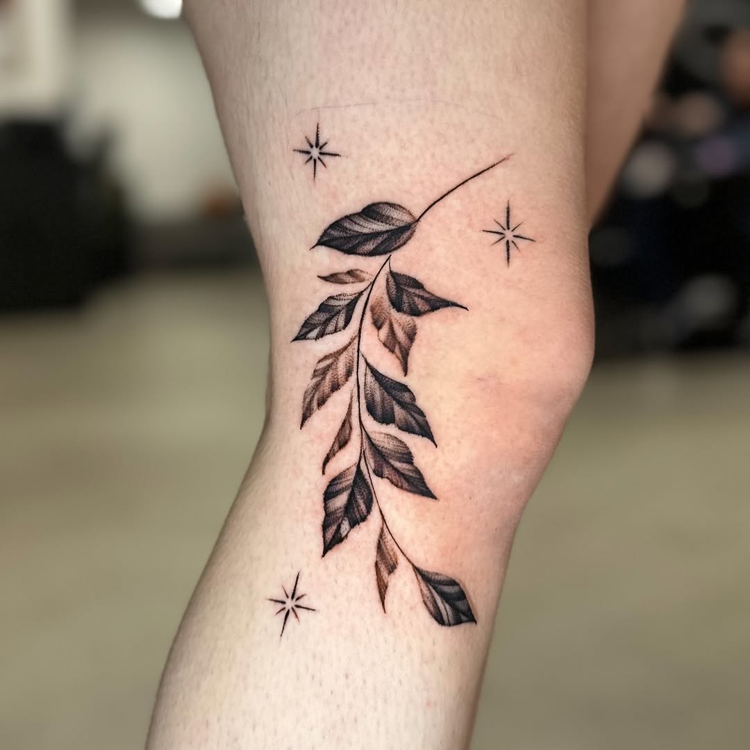 Elegant knee tattoo design featuring leaves and stars.