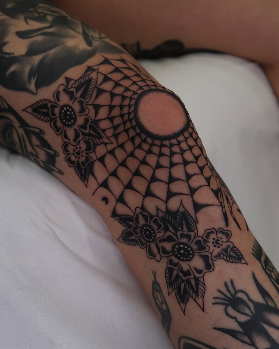 Striking knee tattoo with spider web design