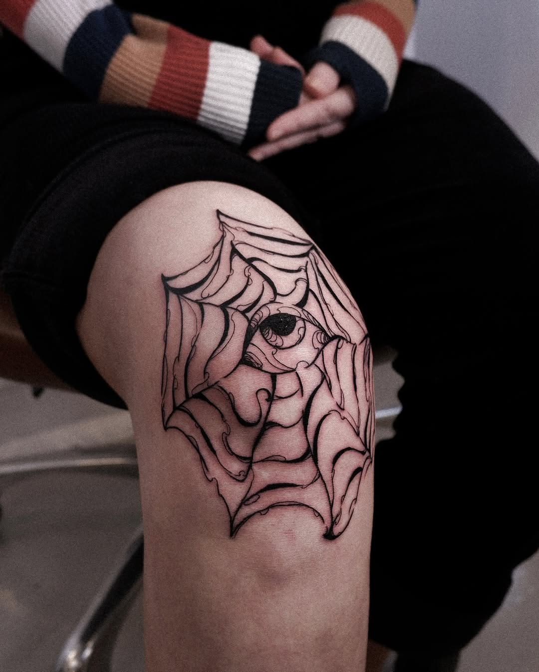 Intricate eye and web knee tattoo design