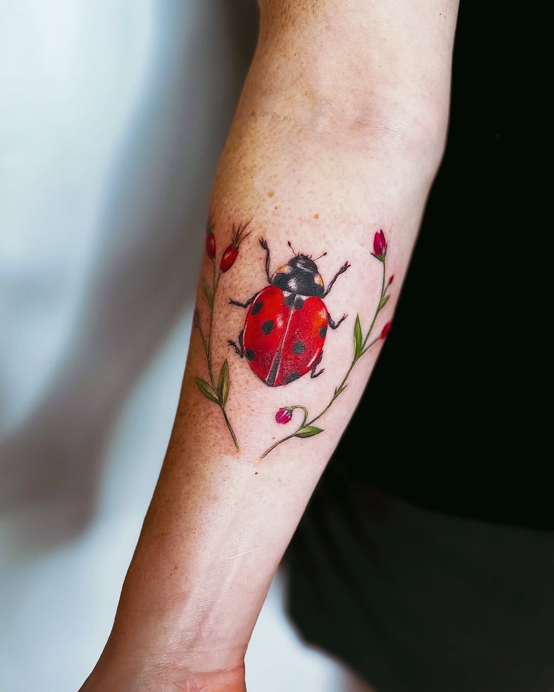 Colorful ladybug tattoo with floral accents