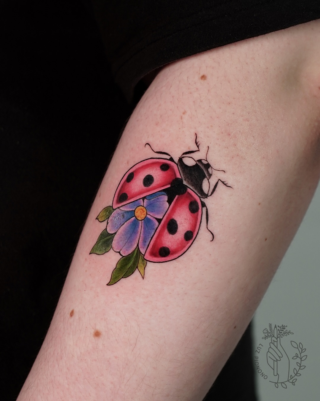 Intricate ladybug tattoo with vibrant floral elements