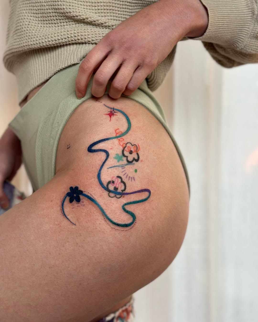 Colorful flower and line tattoo on the hip