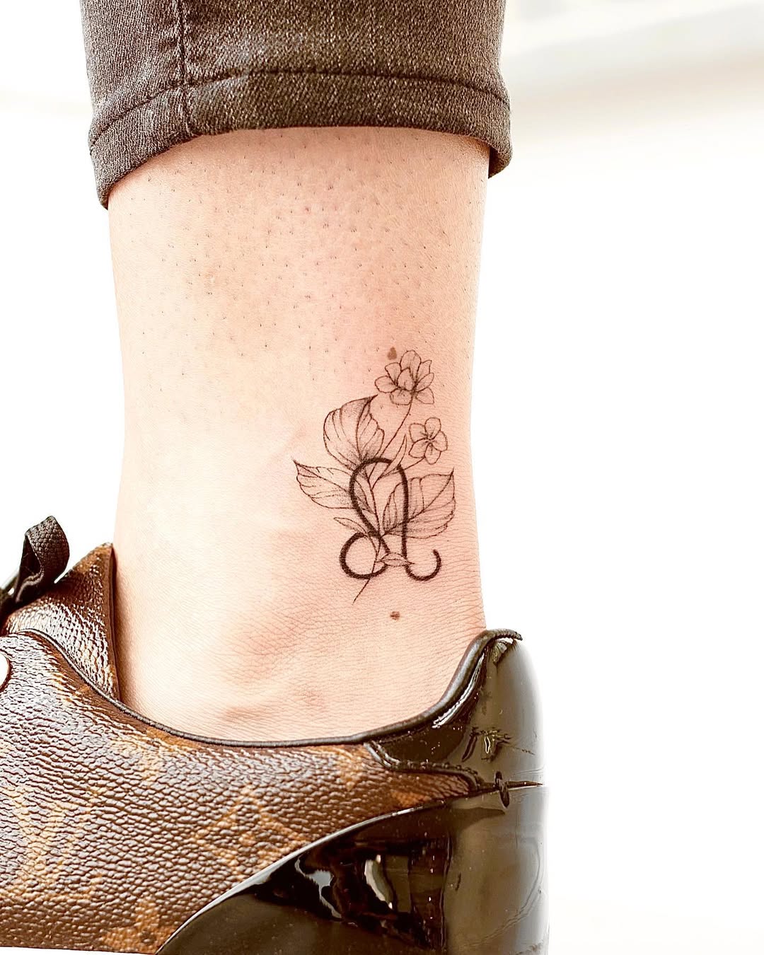 Delicate floral Leo tattoo on ankle