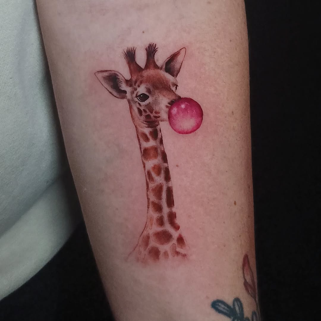 Playful giraffe tattoo with bubble gum charm