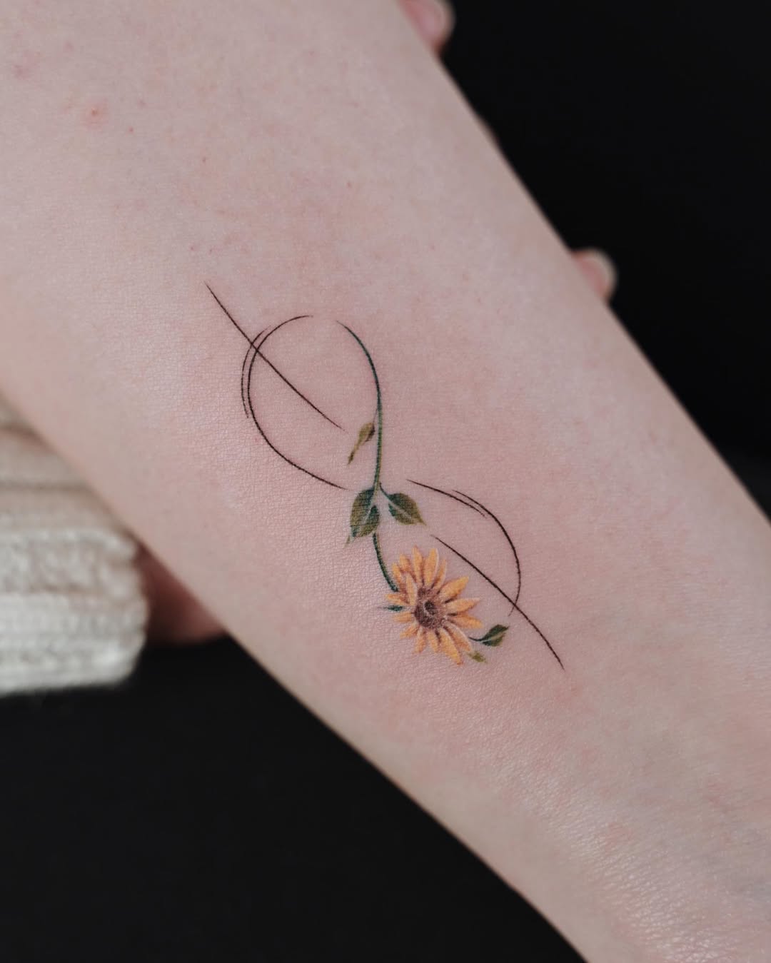 Delicate infinity tattoo with sunflower motif