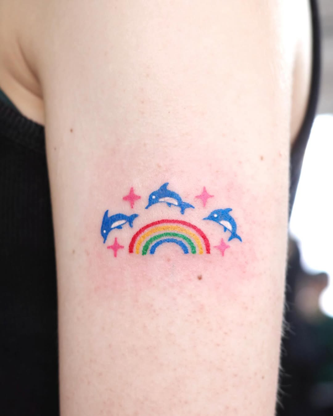 Playful dolphin tattoo with rainbow and stars