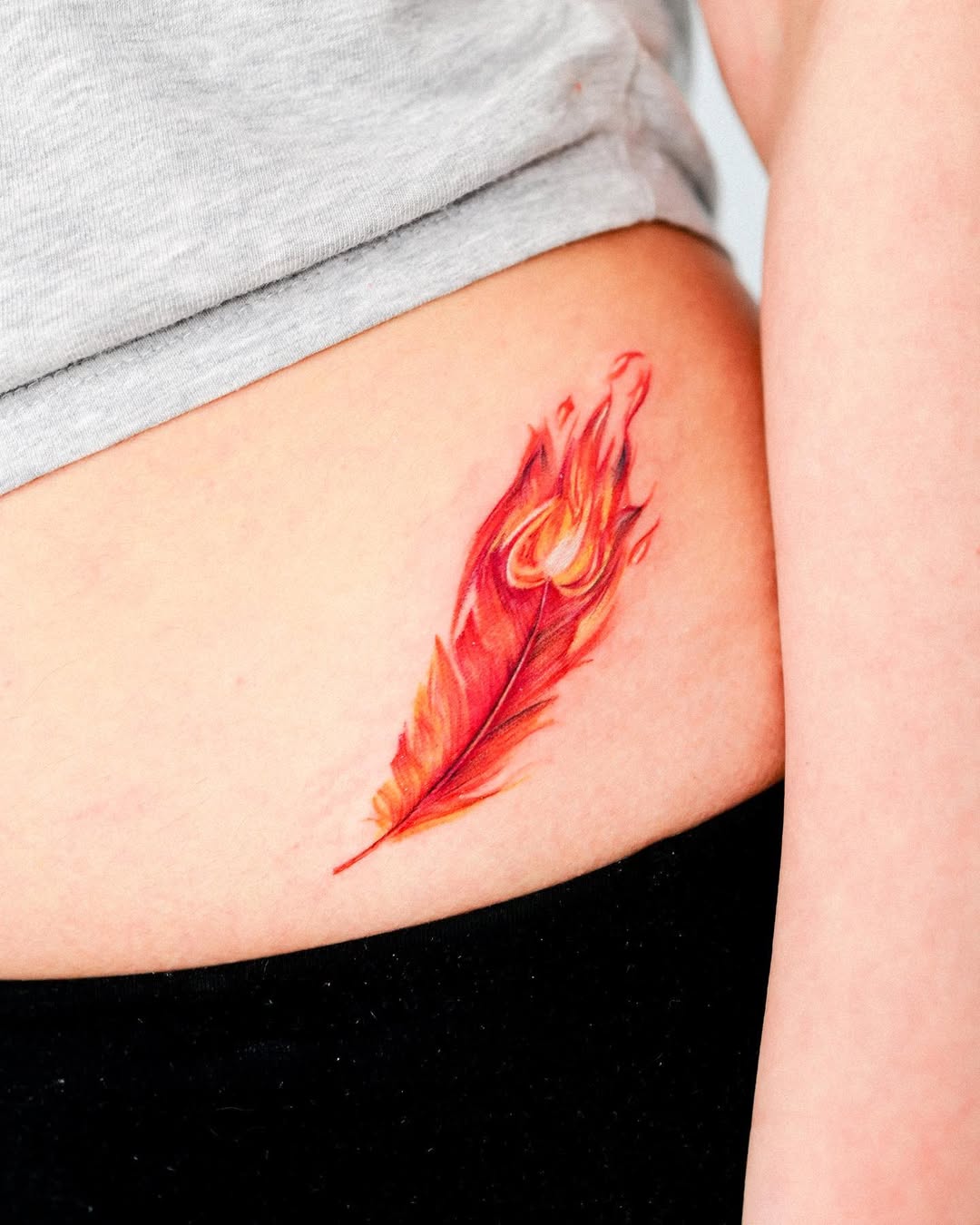 Vibrant Red Feather Tattoo with Flame Embellishments