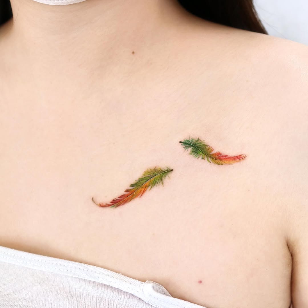 Vibrant feather tattoos on the collarbone area