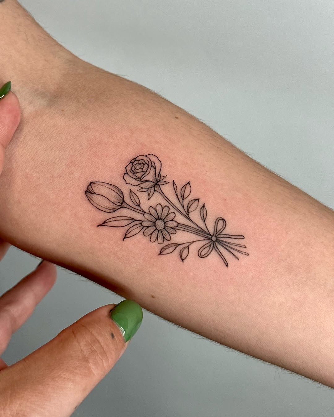Delicate floral arrangement in fine line tattoo