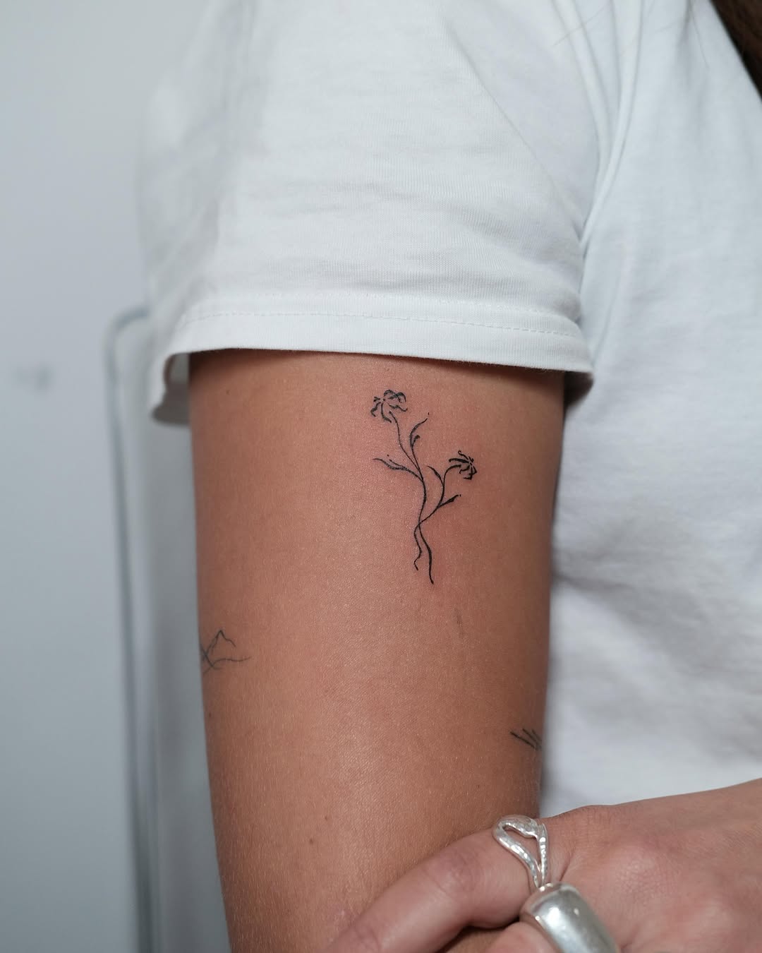 Elegant fine line flower tattoo on arm