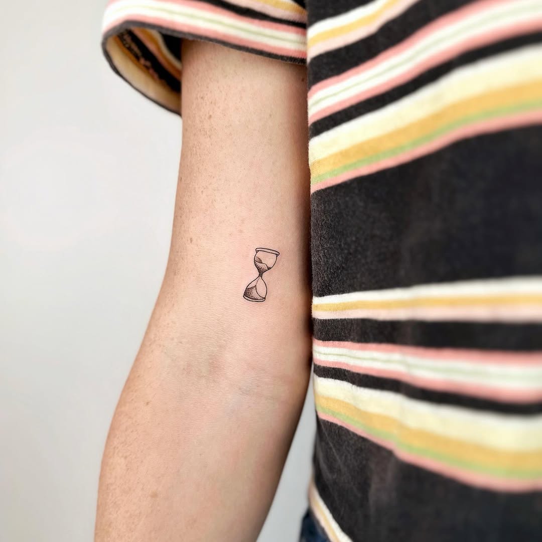 Elegant fine line hourglass tattoo on the arm