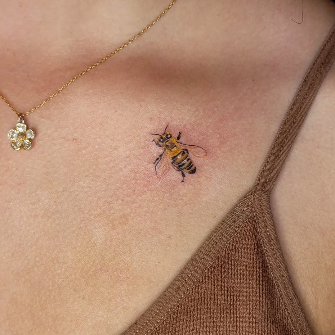 Charming realistic bee tattoo on the collarbone
