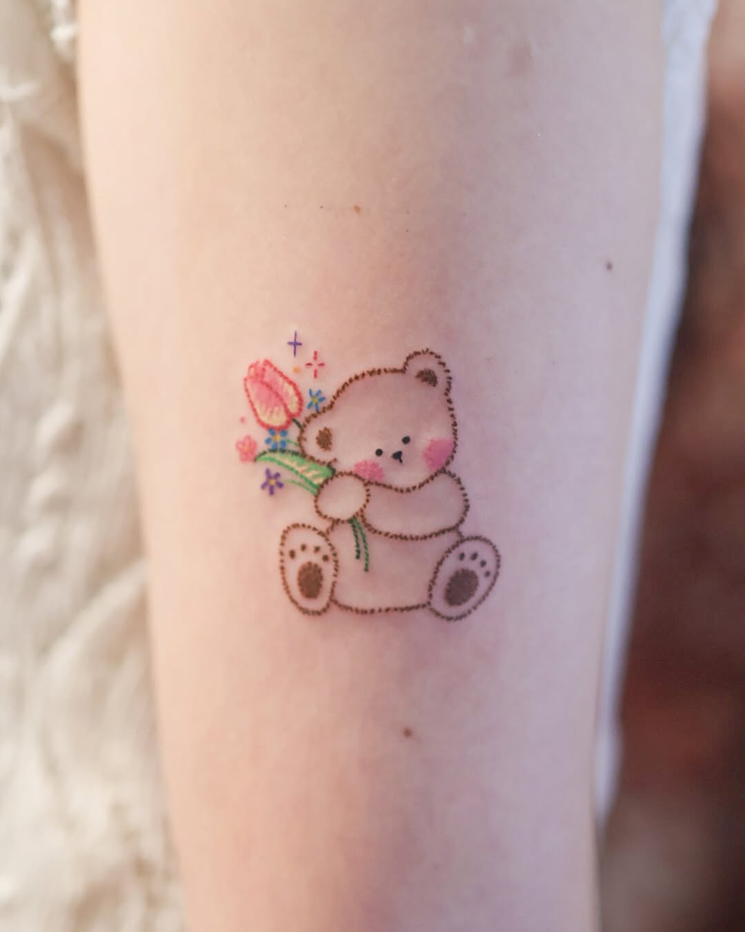 Adorable bear tattoo holding a flower