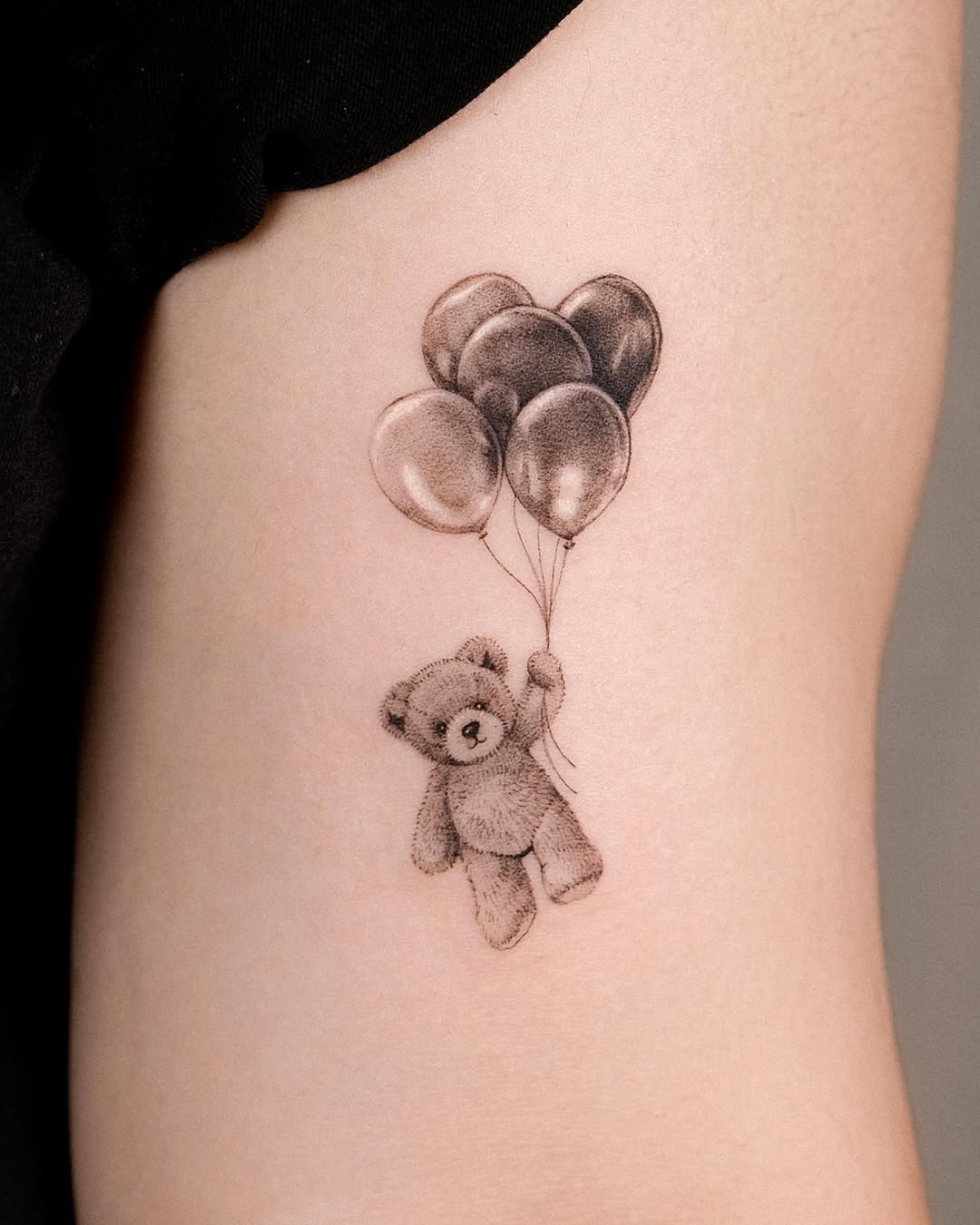 Charming bear tattoo lifting with balloons