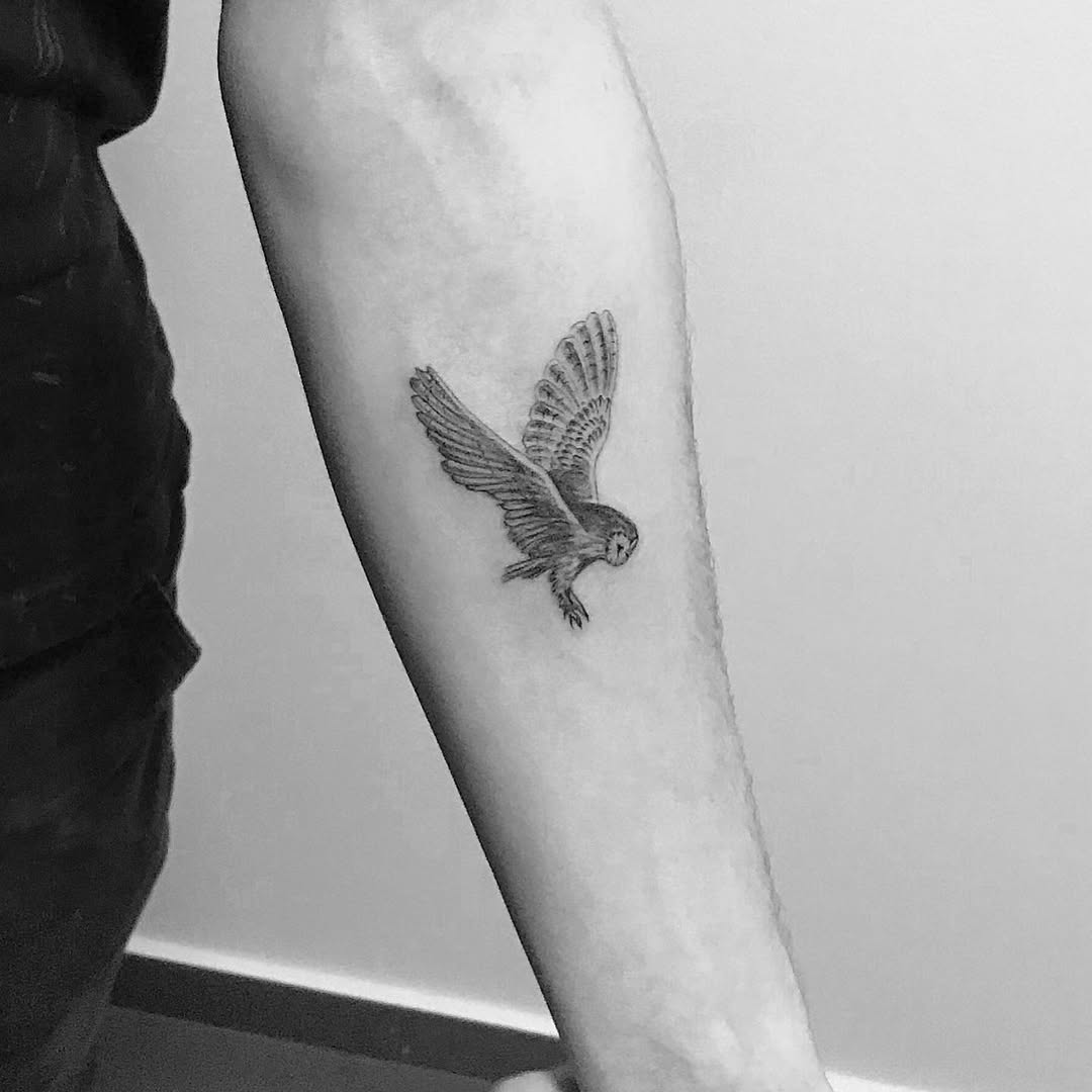 Intricate flying owl tattoo on forearm