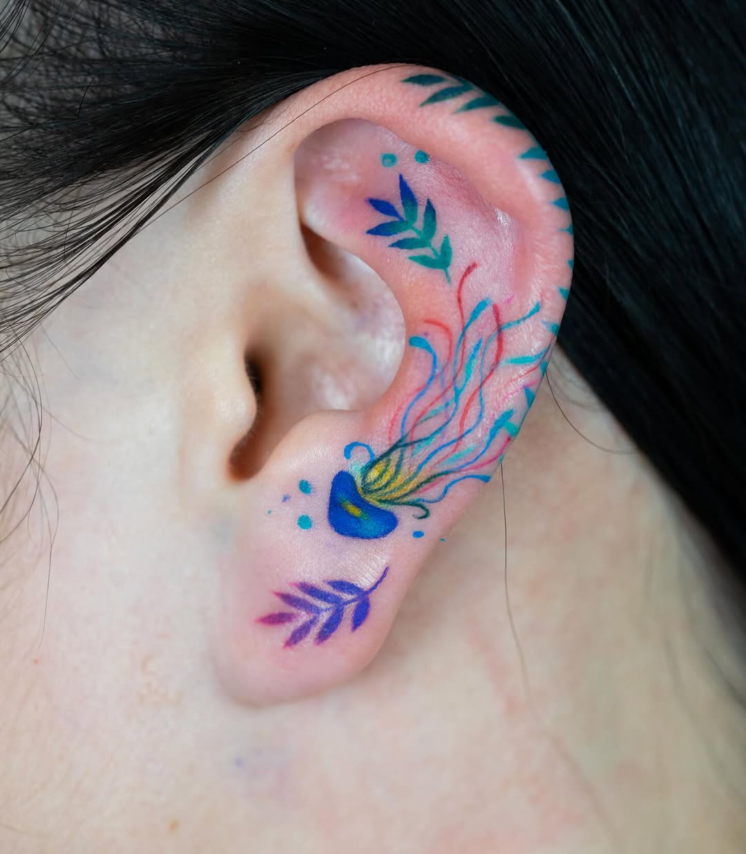 Vibrant jellyfish tattoo nestled in the ear