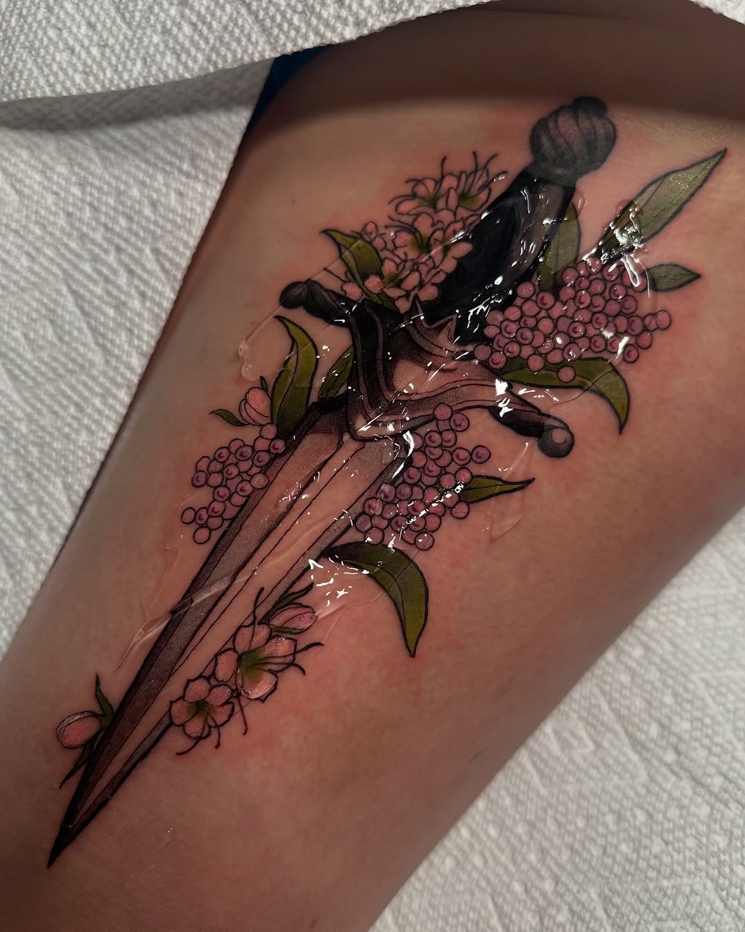 Elegant dagger tattoo adorned with floral elements