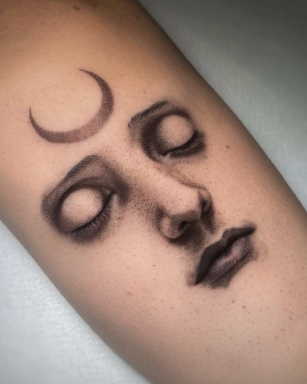 Serene face tattoo with crescent moon detail