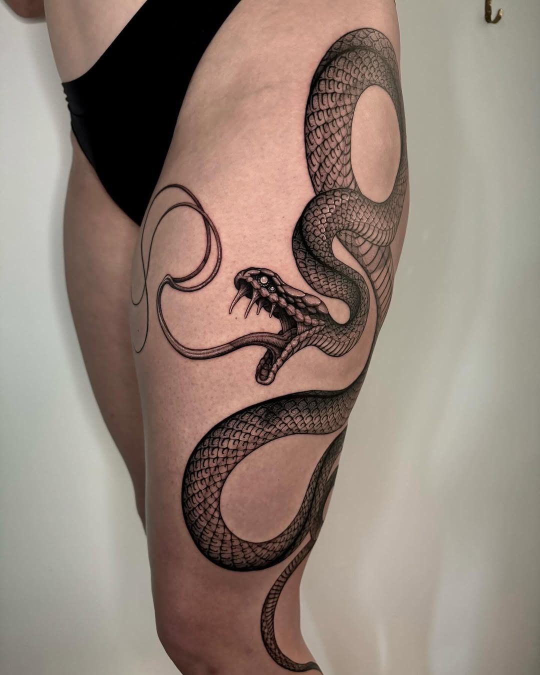 Intricate snake tattoo wrapping around the thigh