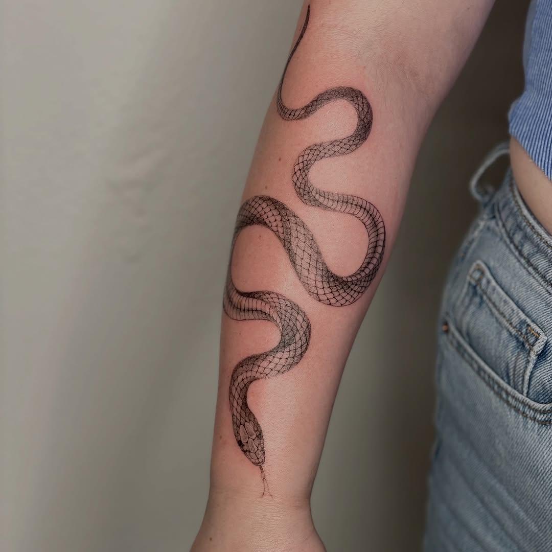 Elegant minimalist snake tattoo on forearm