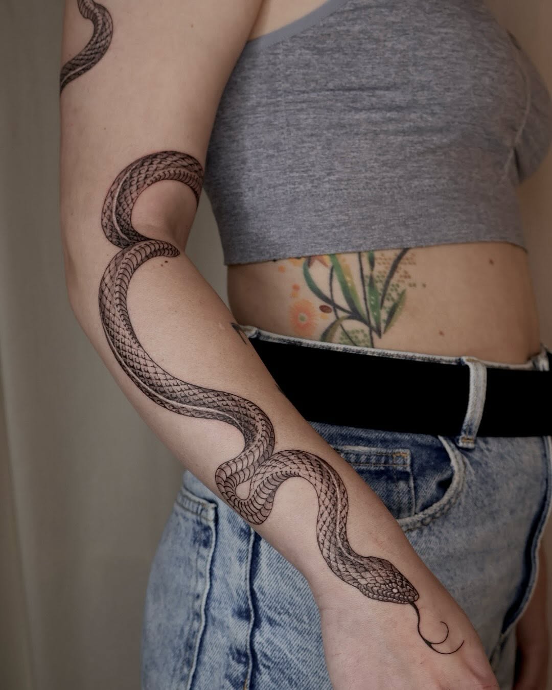 Intricate snake tattoo wraps around the arm