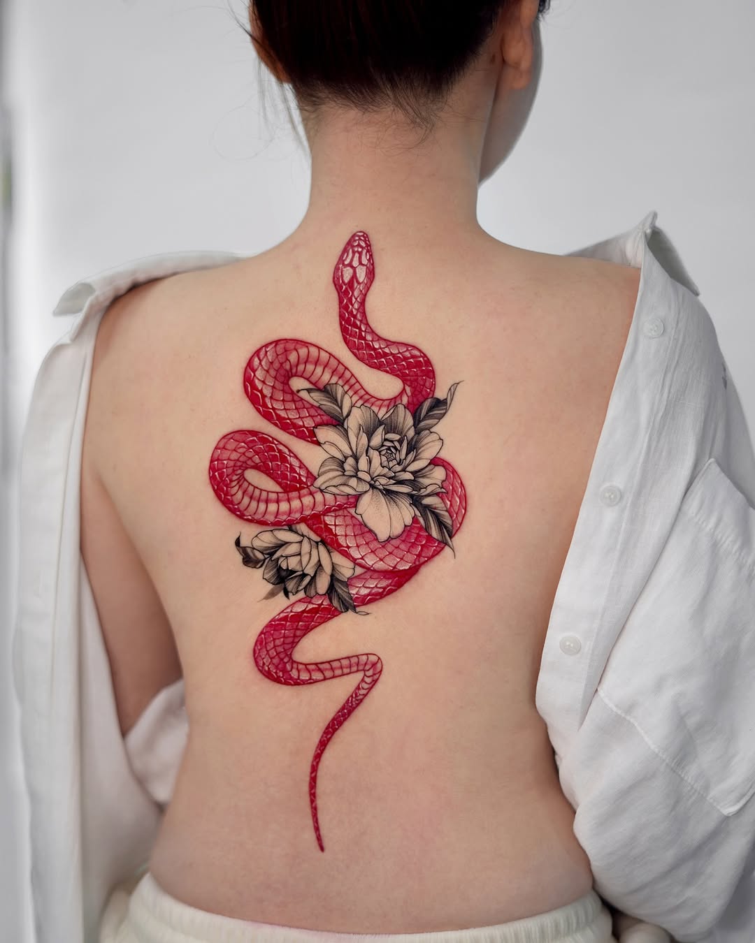 Elegant red snake tattoo with floral accents