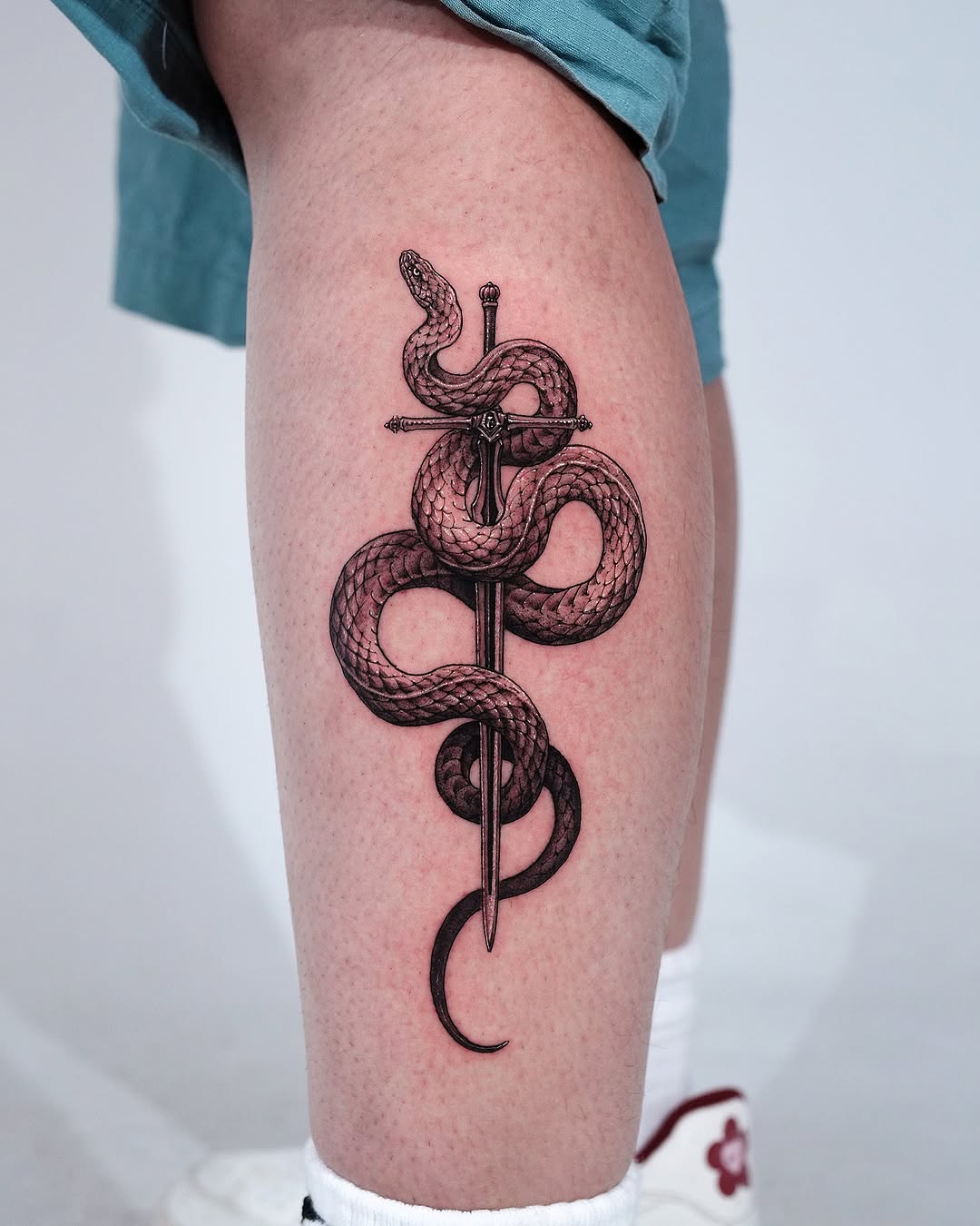 Striking snake and sword tattoo design
