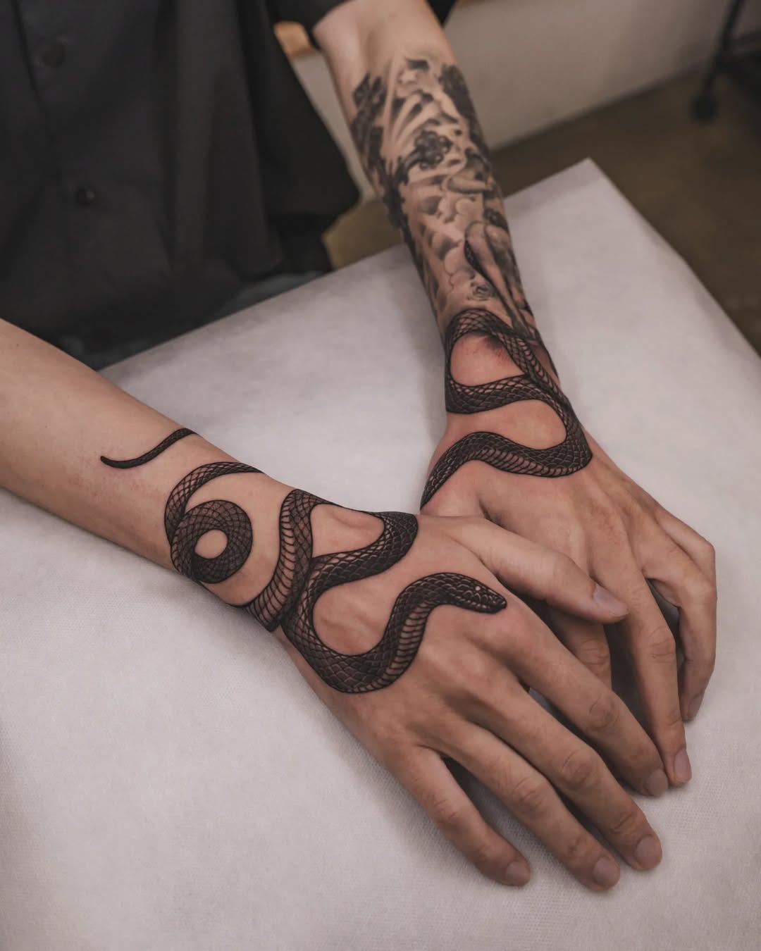 Intricate black snake tattoos on hands