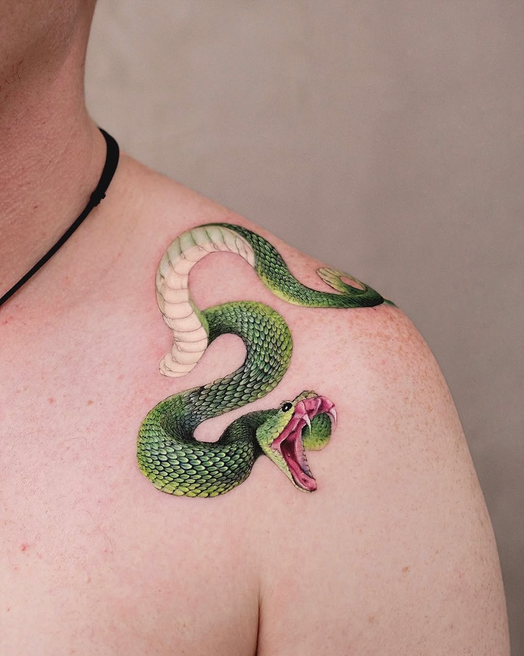 Dynamic green snake tattoo on shoulder