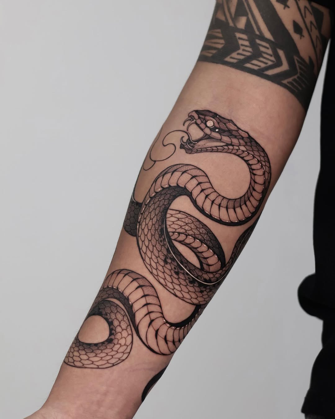 Intricate black ink snake tattoo on forearm