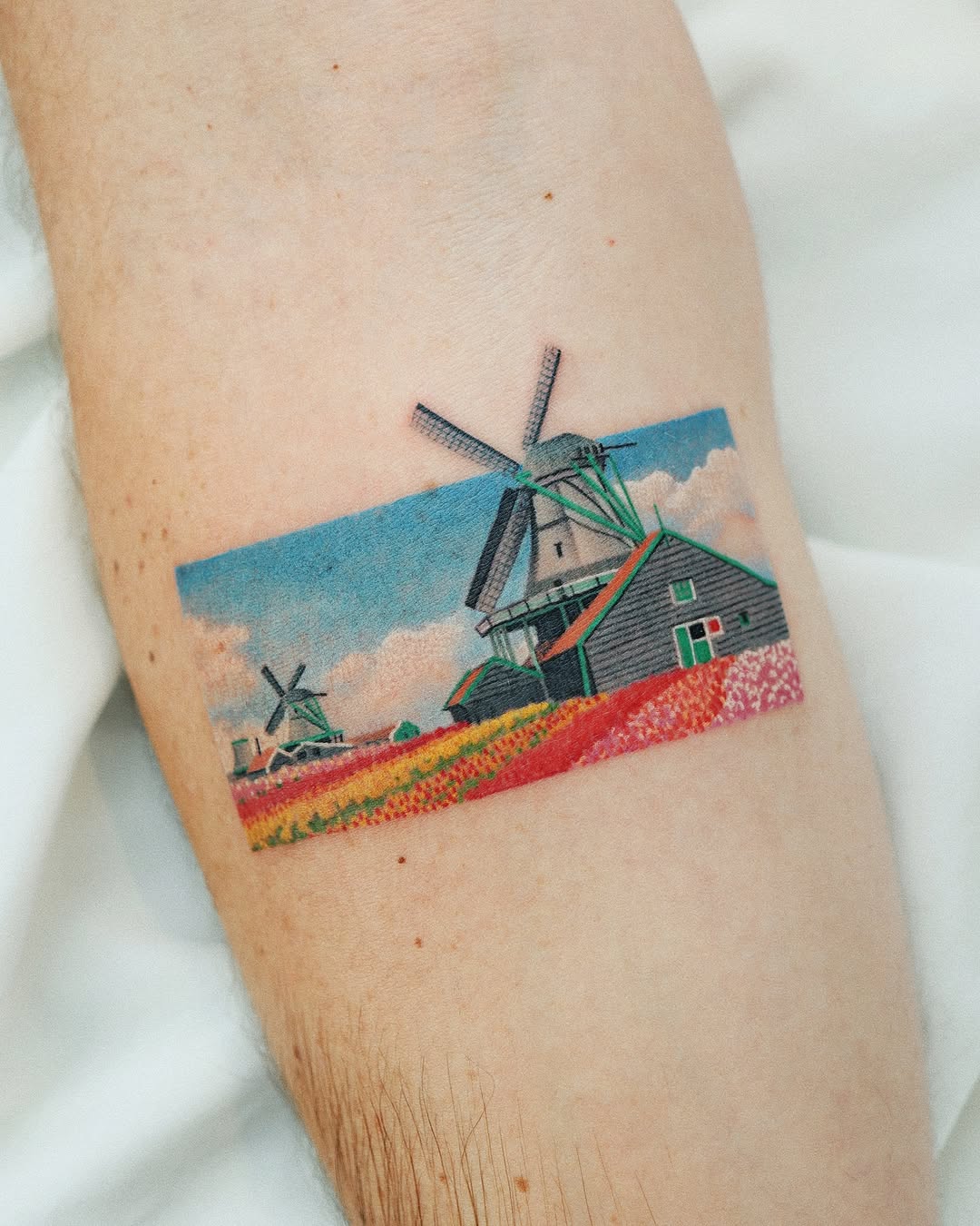 Vibrant landscape tattoo showcasing a serene windmill scene