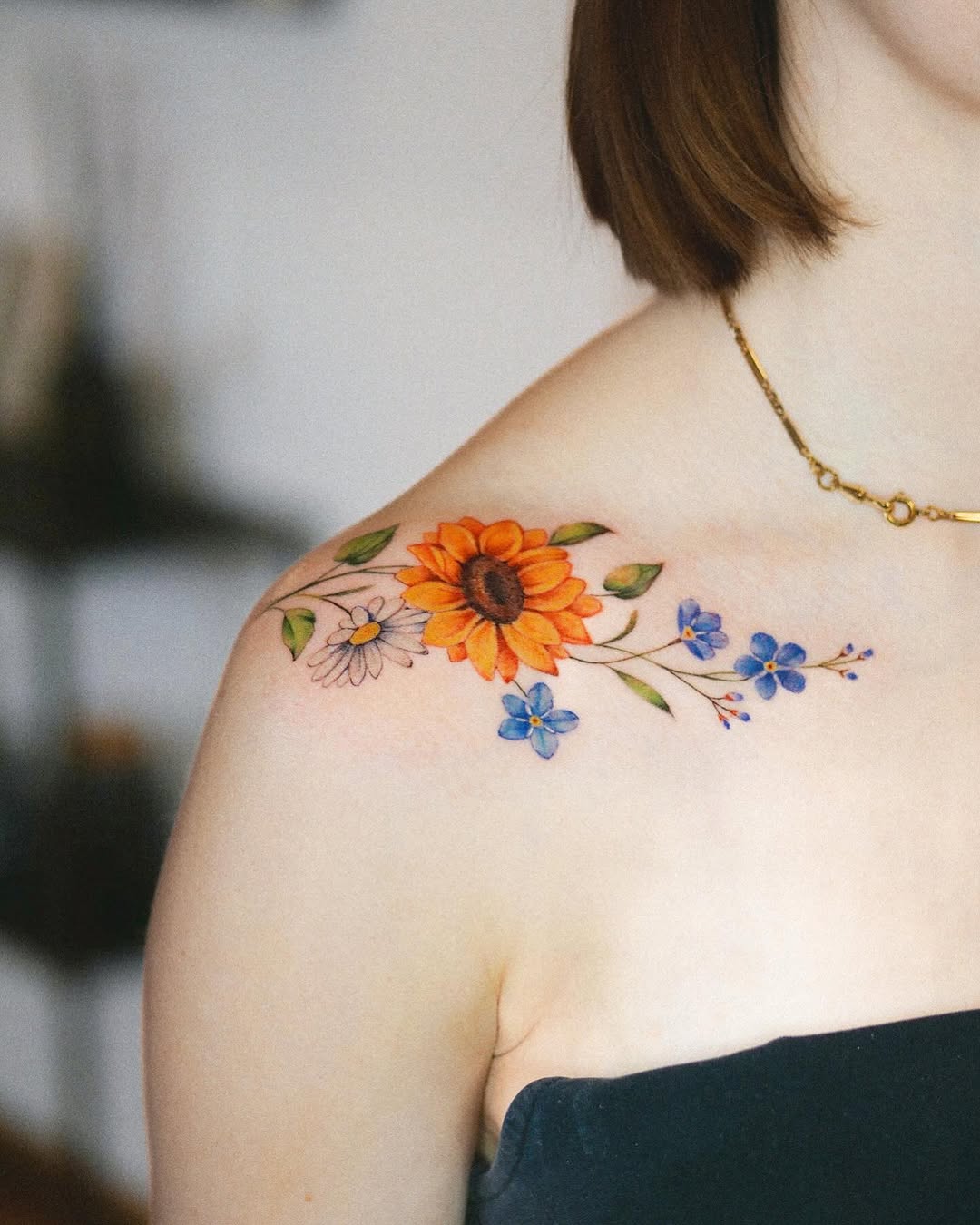 Vibrant sunflower tattoo adorns shoulder gracefully