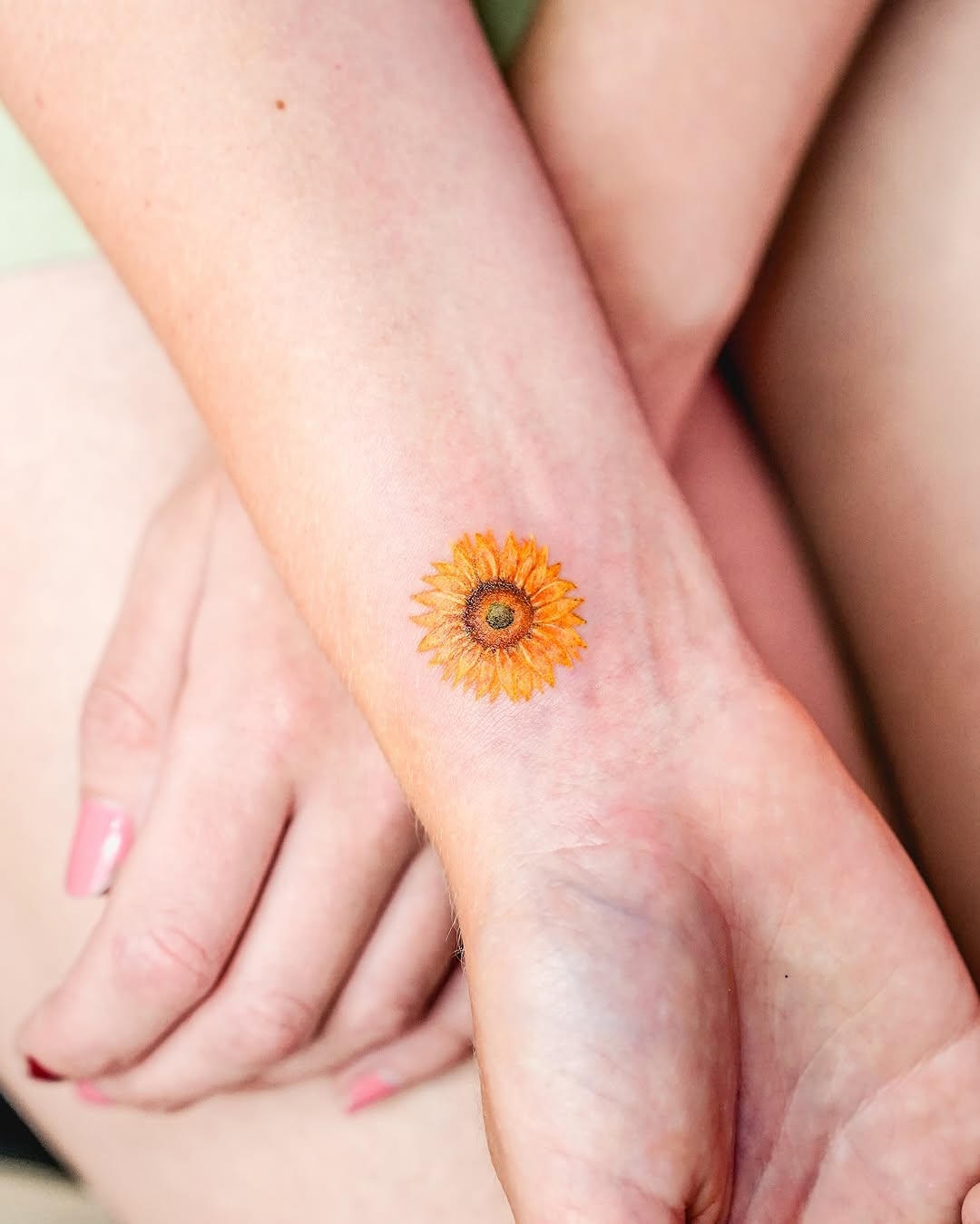 Vibrant sunflower tattoo on a wrist.