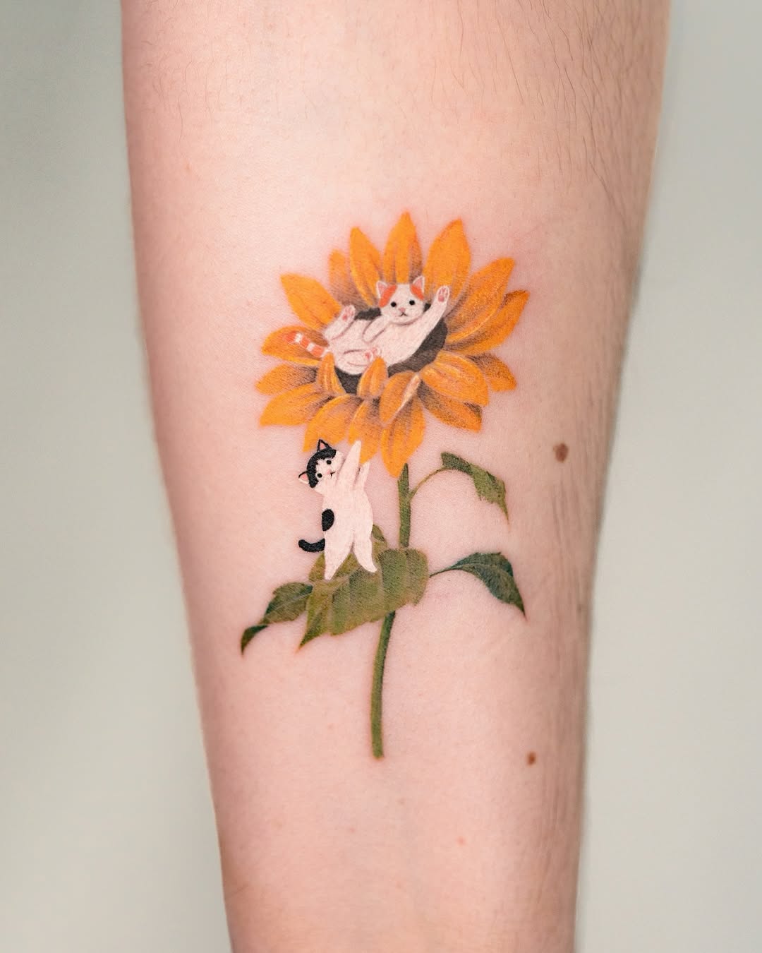 Whimsical sunflower tattoo featuring playful cats